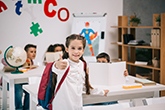 Skolflicka i klassrum gör tummen upp. Foto: LightField, MostPhotos